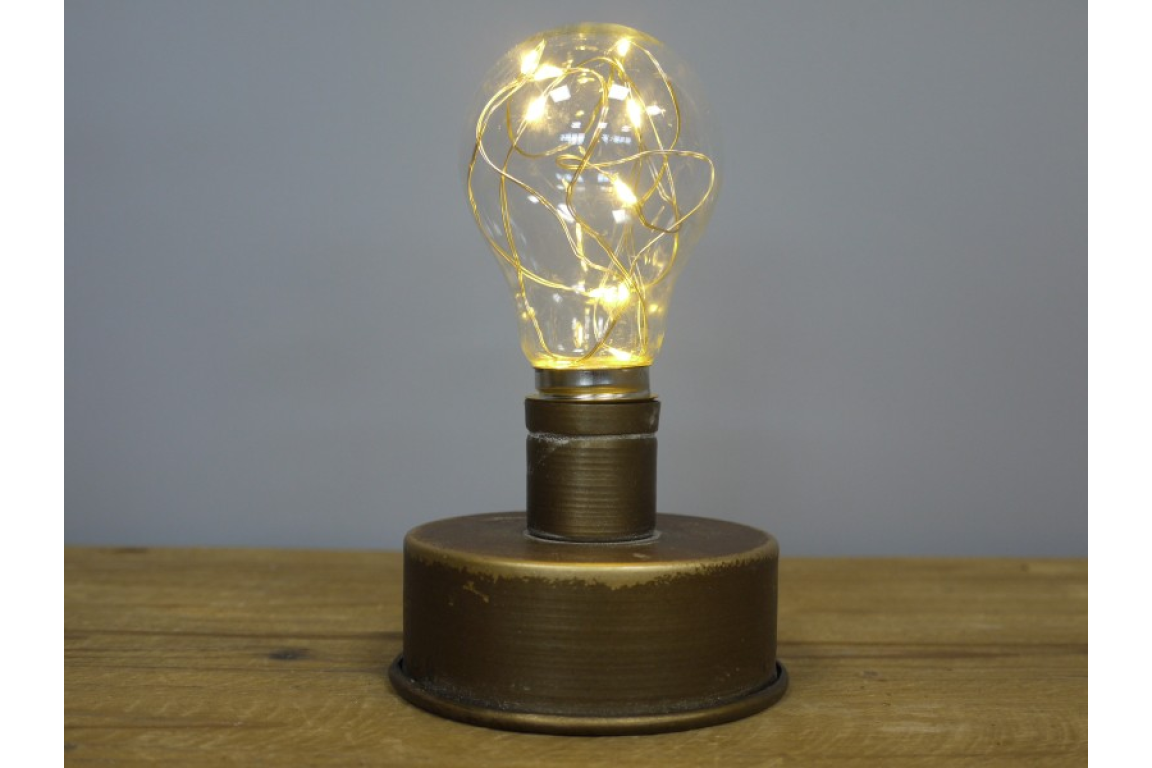 Small industrial-style light with round bronze metal base and bulb-shaped glass cover with warm LED string lights.