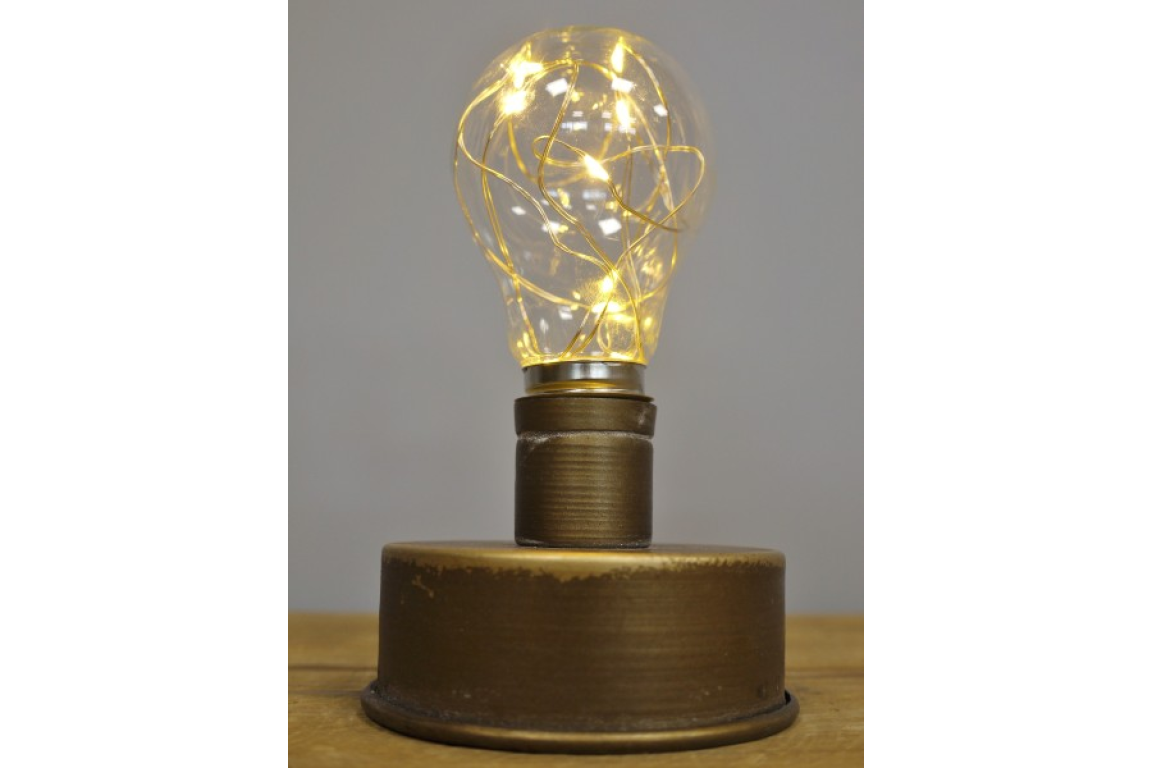 Small industrial-style table light with cylindrical bronze metal base and clear glass bulb with warm LED string lights