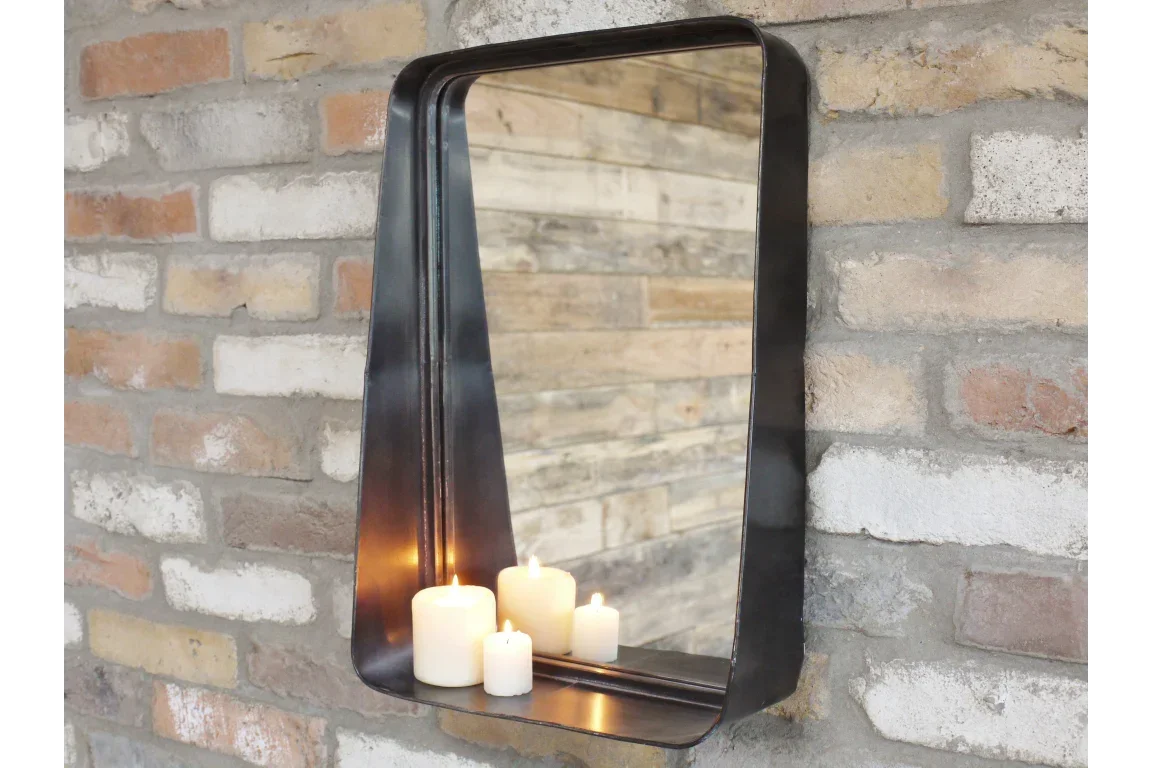Black metal wall mirror with shelf and candles on exposed brick wall