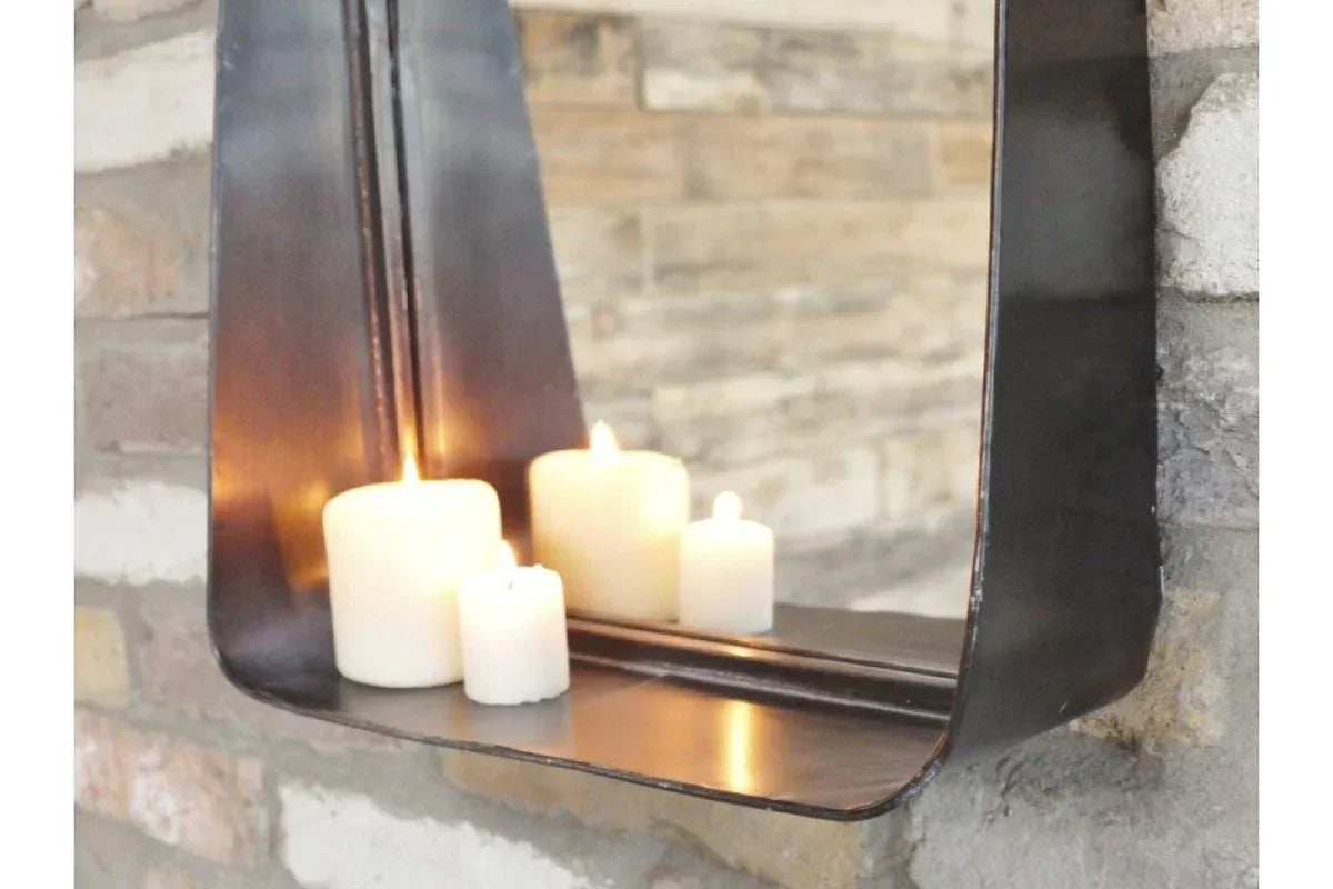 Wall mirror with black metal frame and shelf holding lit pillar candles