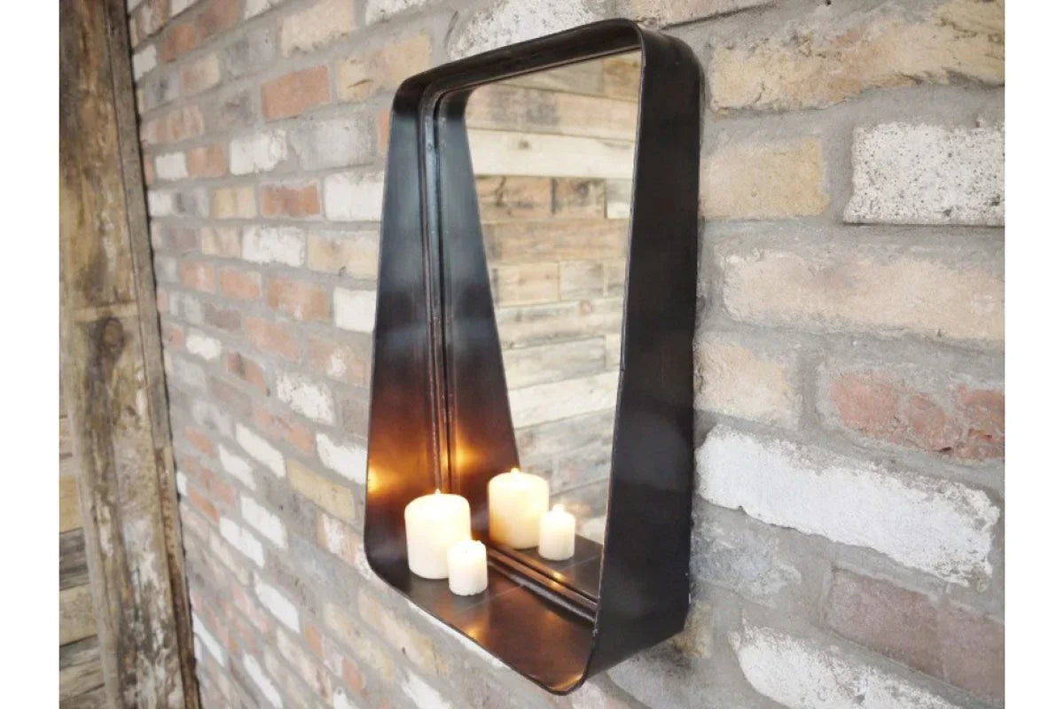 Industrial wall mirror with black metal frame and shelf holding candles on brick wall