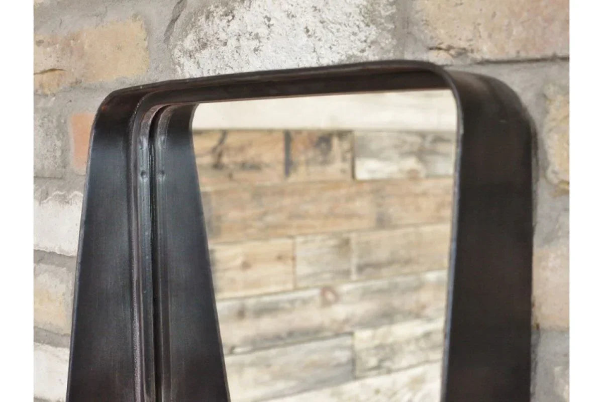 Industrial wall mirror with black metal frame against exposed brick and wood backdrop