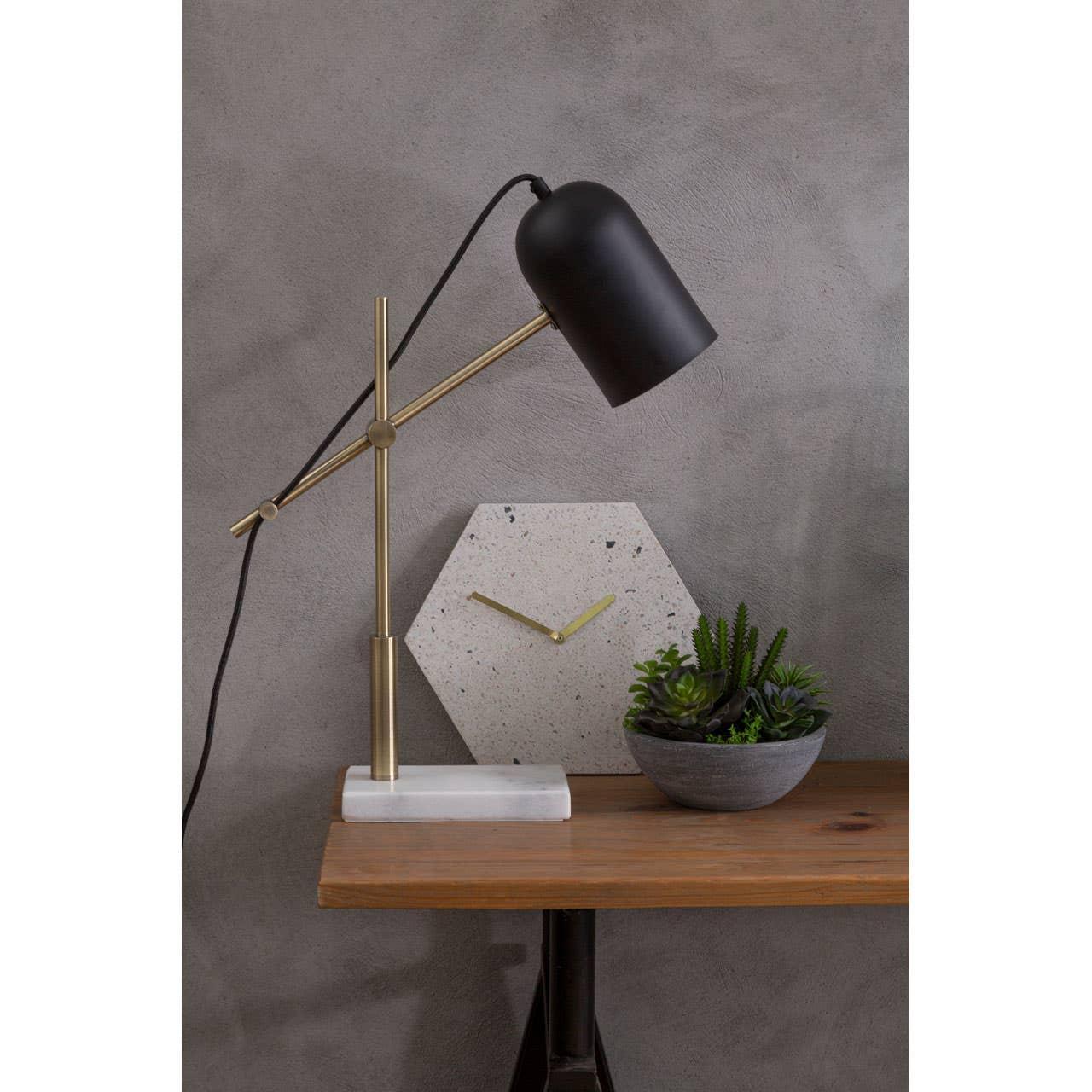 Brass and black desk lamp on wooden table with hexagonal clock and small succulent plant