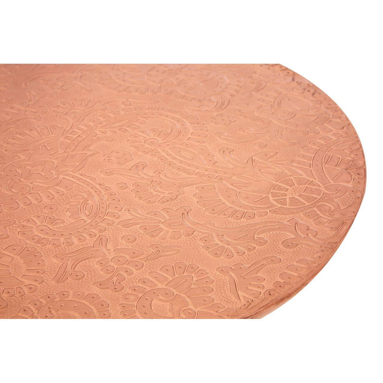 Round copper table top with embossed floral pattern detail close-up