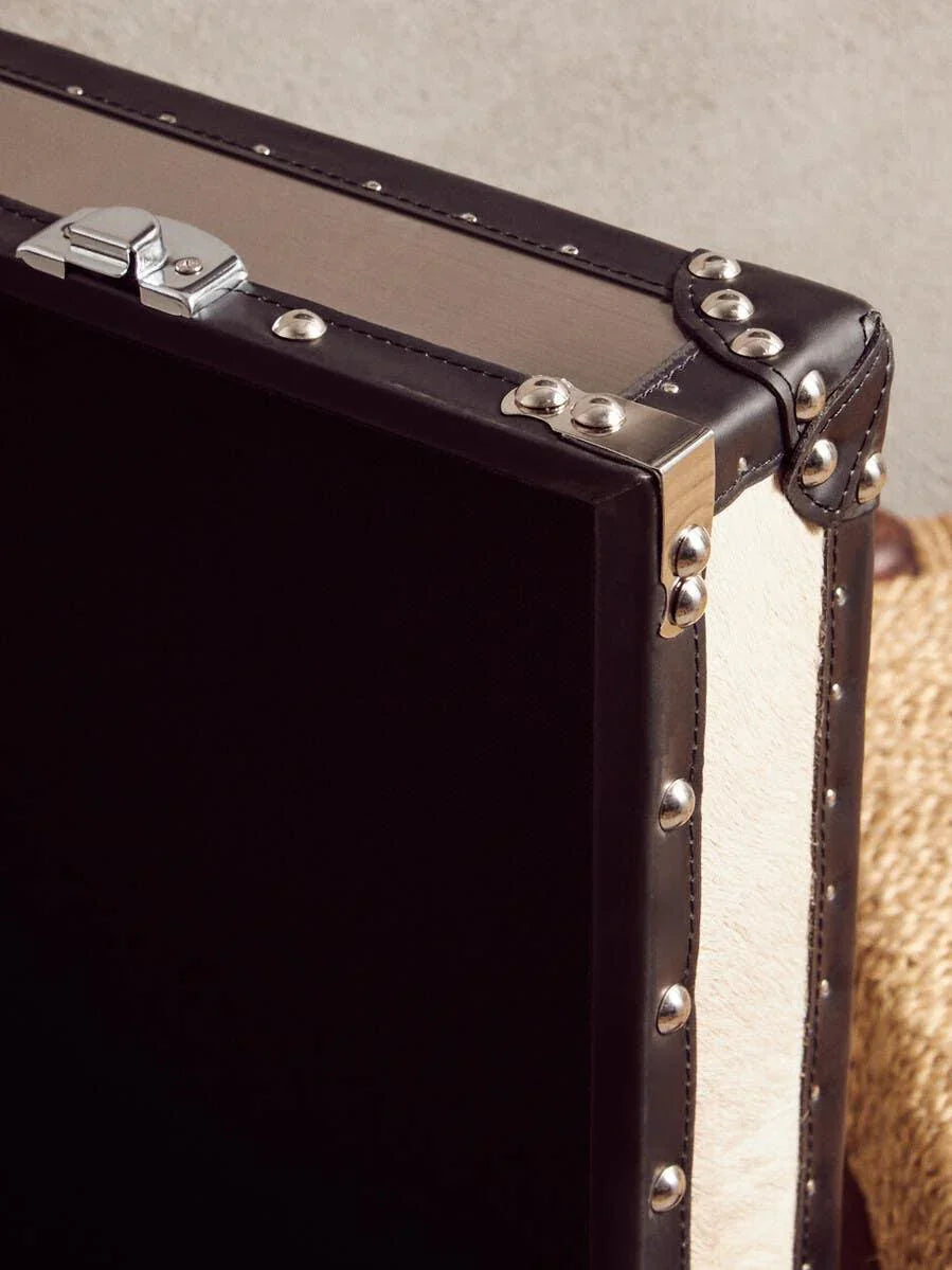 Closeup of black studded storage trunk with metal corners and leather trim detail