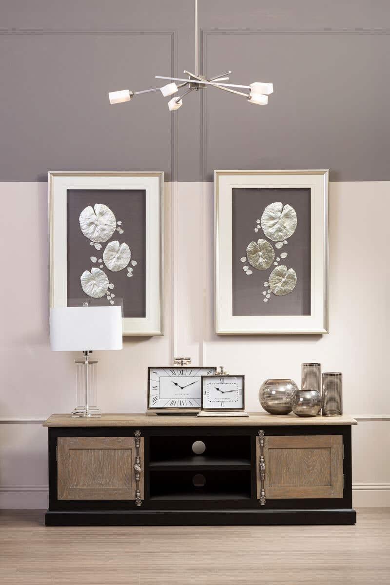 Wood and black sideboard with clocks, glass vases, table lamp and framed wall art