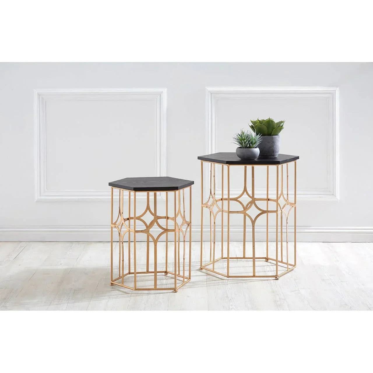 Set of two hexagonal gold metal side tables with black tops, plants displayed on larger table