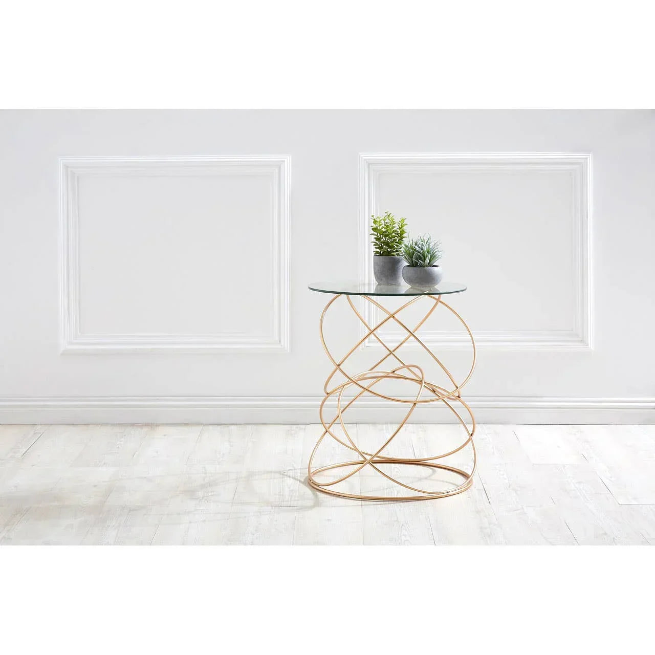 Glass top side table with gold metal base, two potted plants on white wooden floor