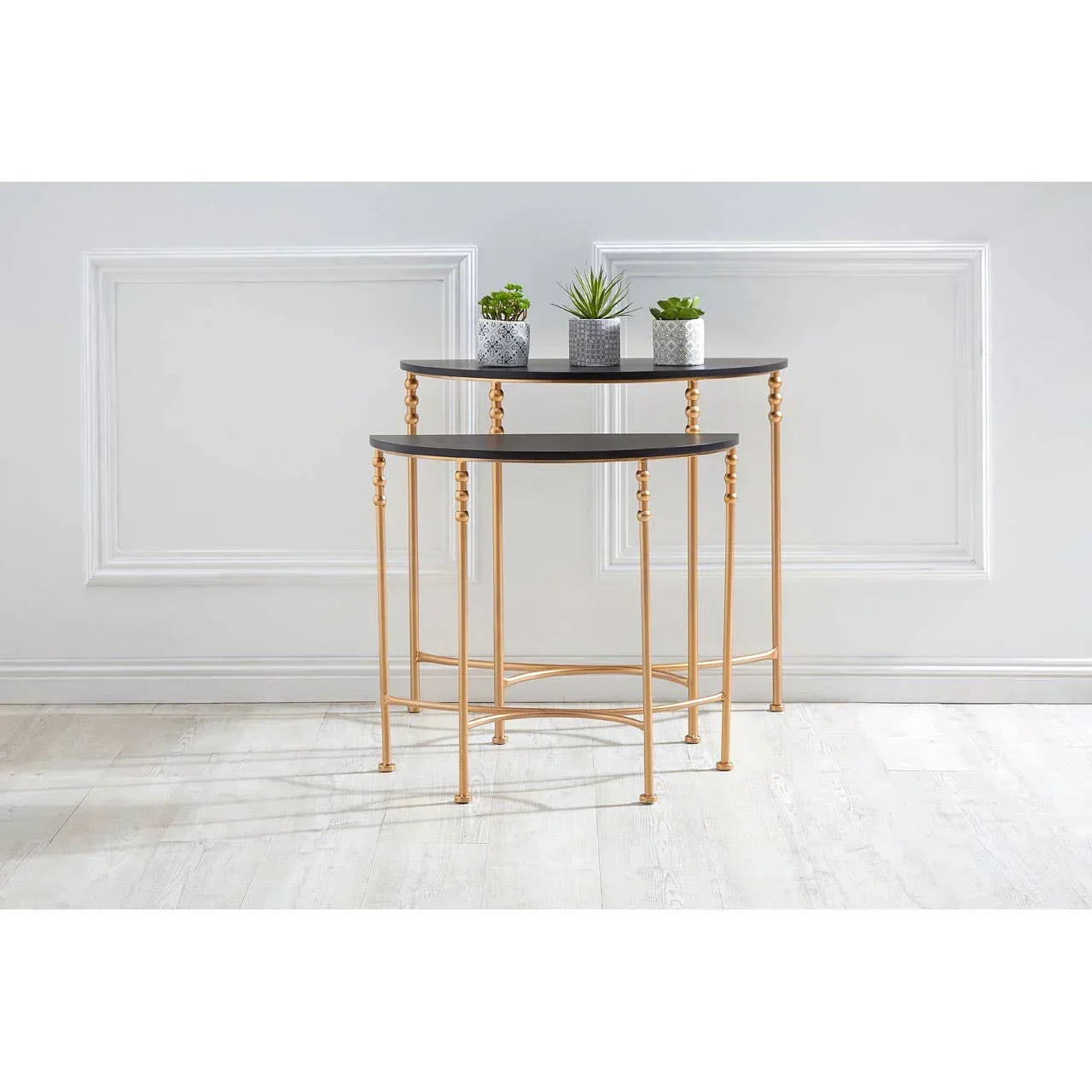 Nesting console tables with gold metal legs and black tops, styled with small potted plants