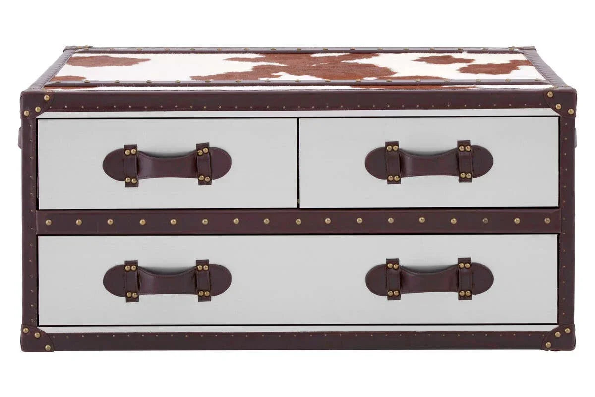 Cowhide trunk style coffee table with four drawers, leather handles, and brass stud accents