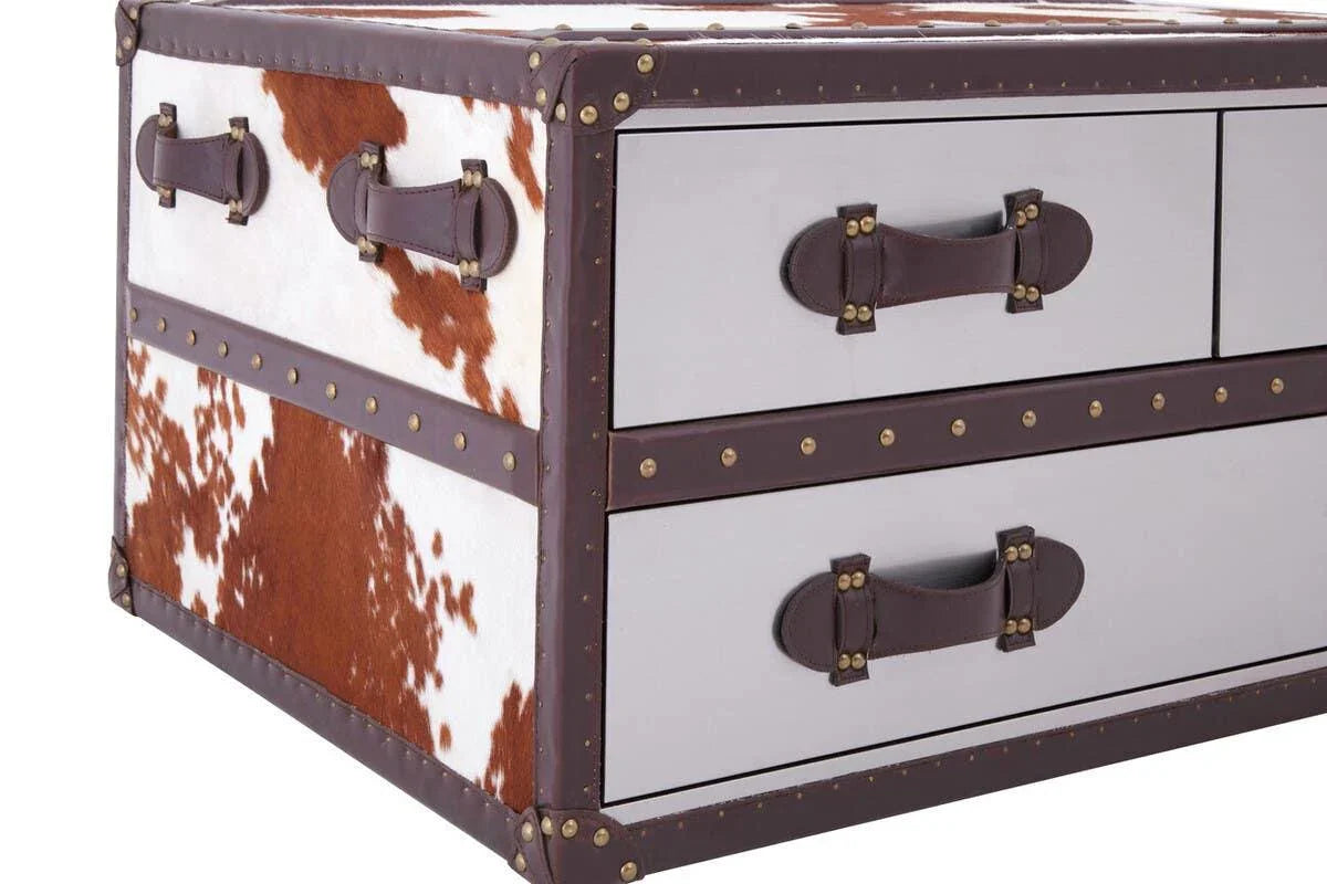 Cowhide storage chest with brown leather trim, brass studs, and side handles