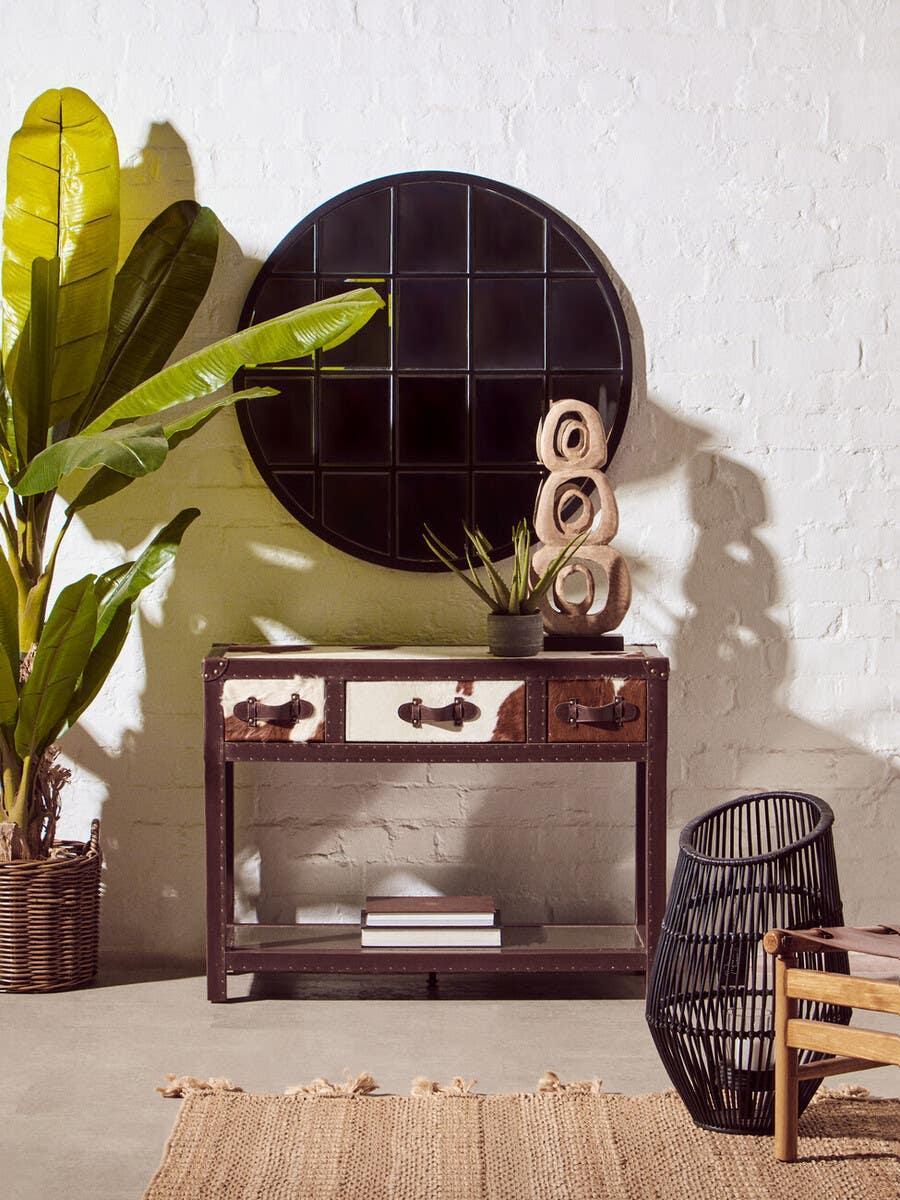 Rustic hallway console table with cowhide drawers, round wall mirror, indoor plant decor