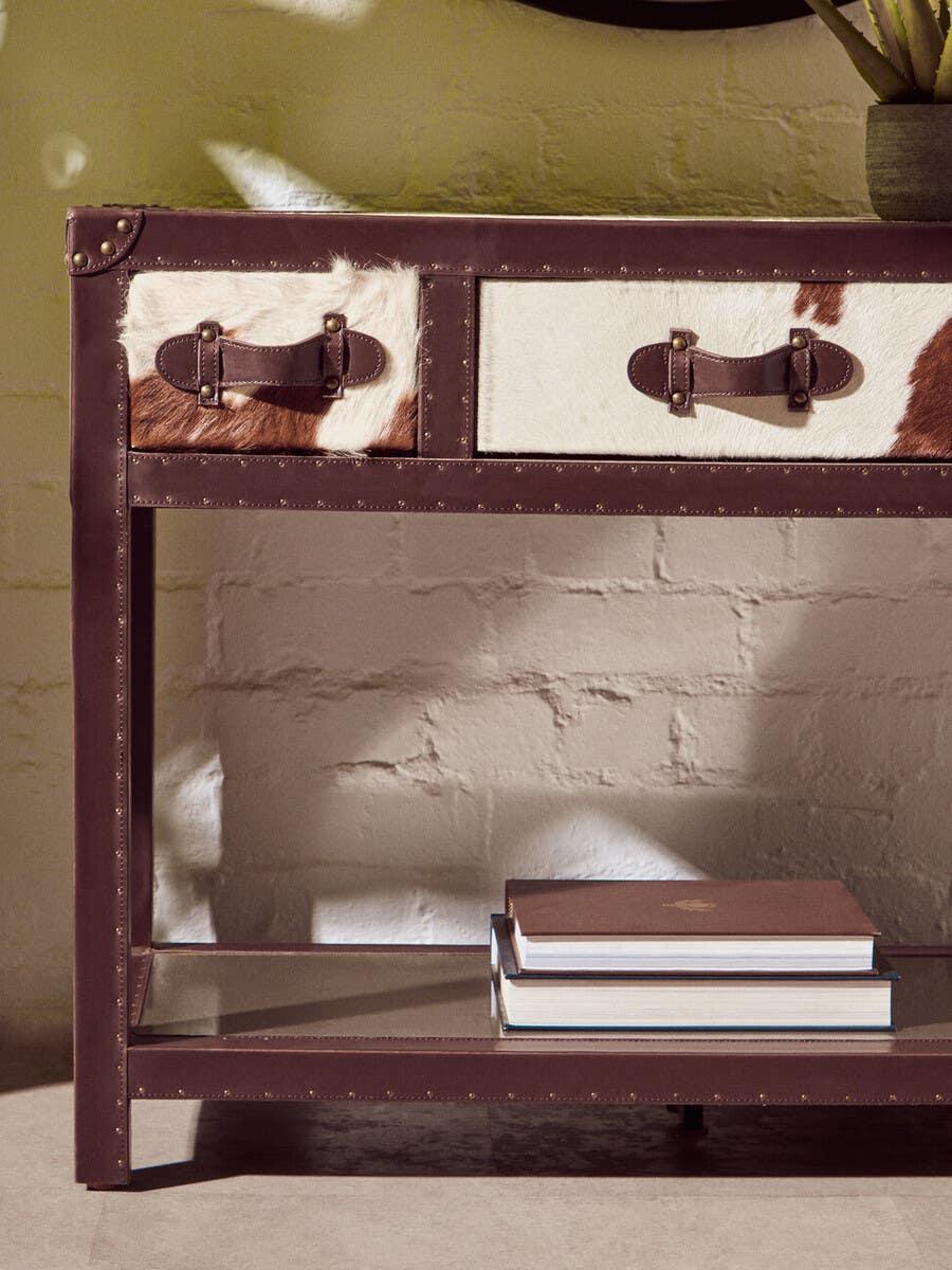 Brown and white cowhide console table with leather details and metal studs