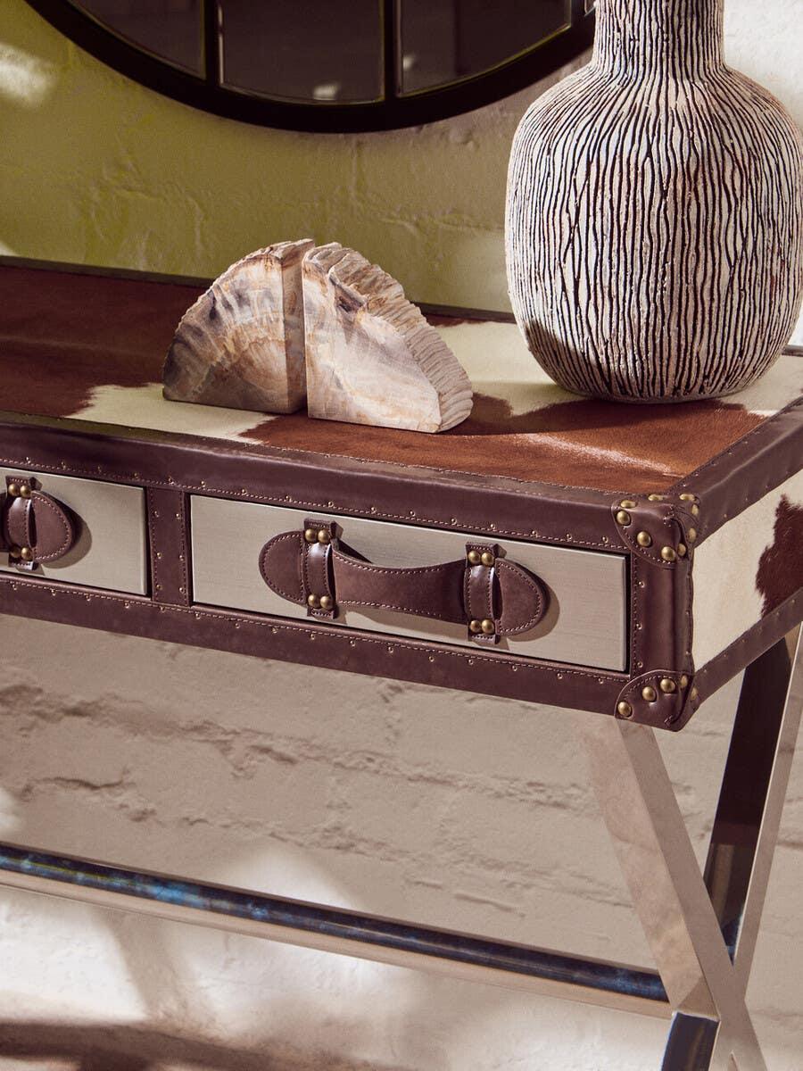 Brown cowhide console table with leather handles and decorative ceramic vase on top
