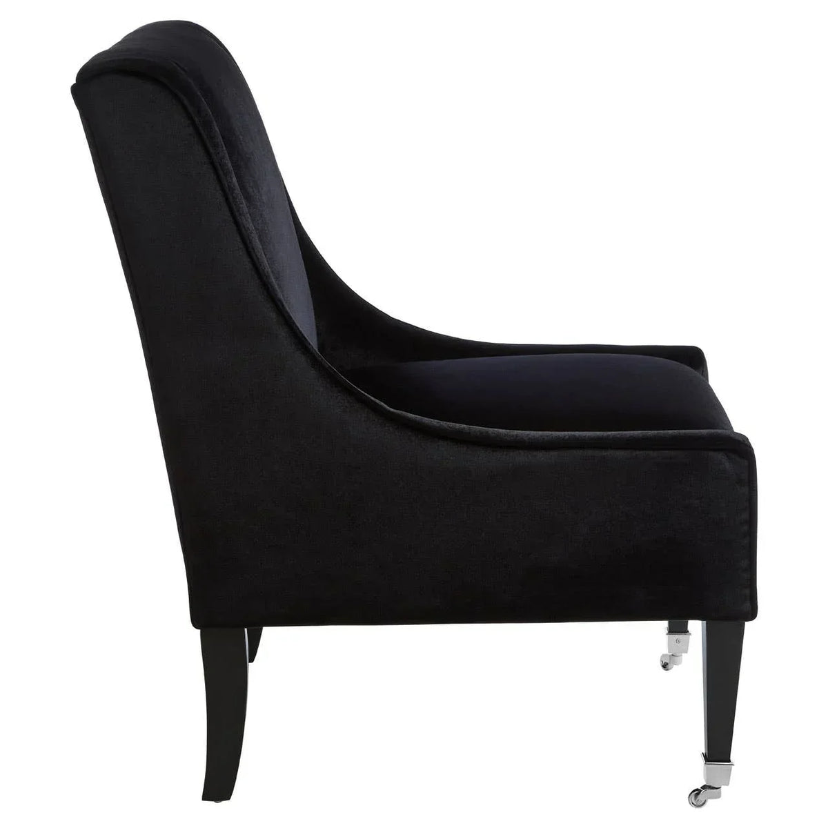 Black velvet accent chair side view with slim legs and front castor wheels