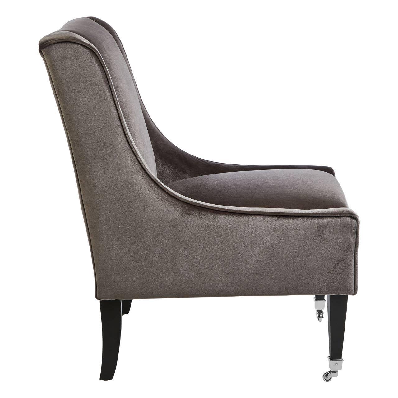 Side view of grey velvet accent chair with dark wooden legs and front castor wheels