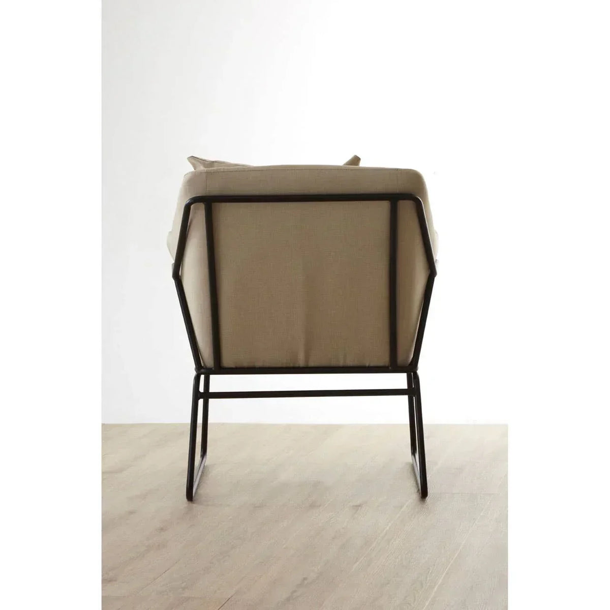 Beige armchair with metal frame shown from the back on a wooden floor