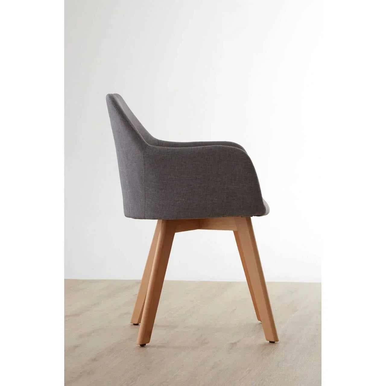 Grey upholstered dining chair with wooden legs side view on light wood floor
