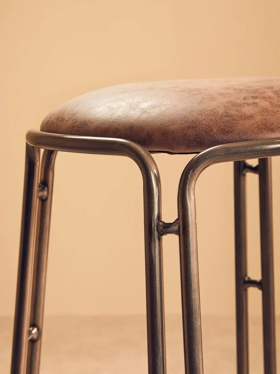 Brown faux leather bar stool with metal legs and welded detail, side close-up