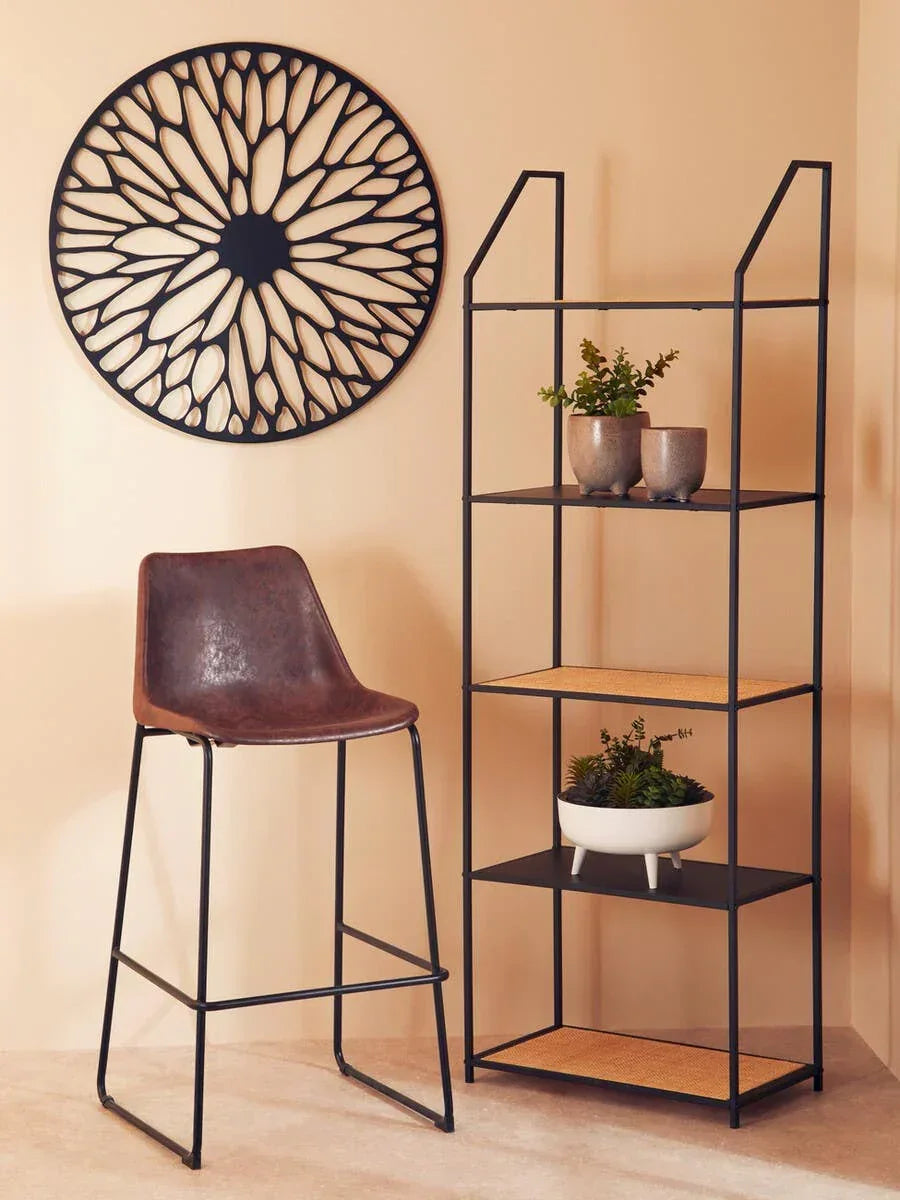 Brown faux leather bar stool with black metal frame next to black metal shelving unit and wall art