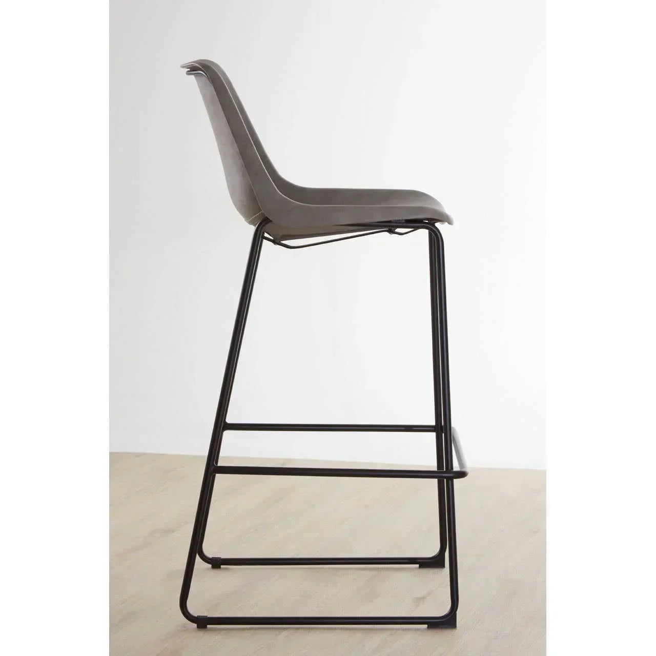 Grey bar stool with curved seat and black metal legs on wooden floor