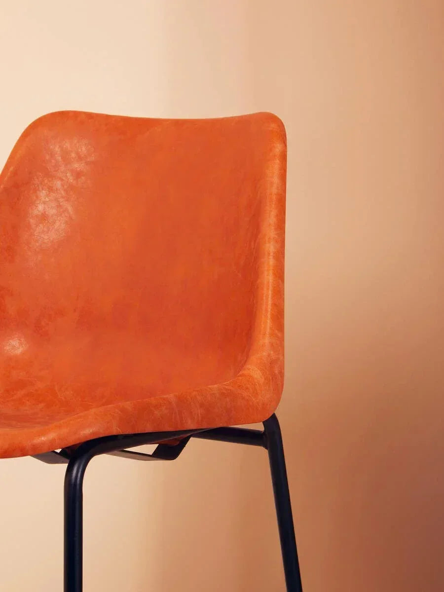 Tan faux leather dining chair with black metal legs side view