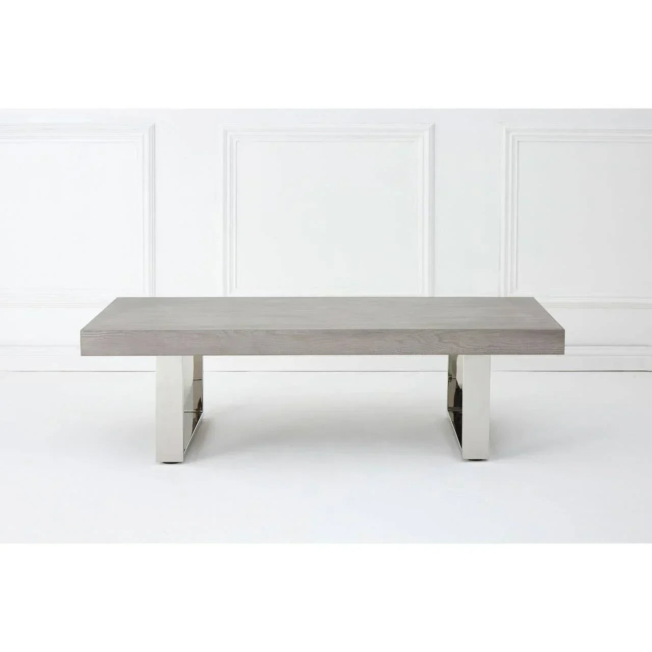 Modern coffee table with grey wood top and chrome legs against white wall panel background