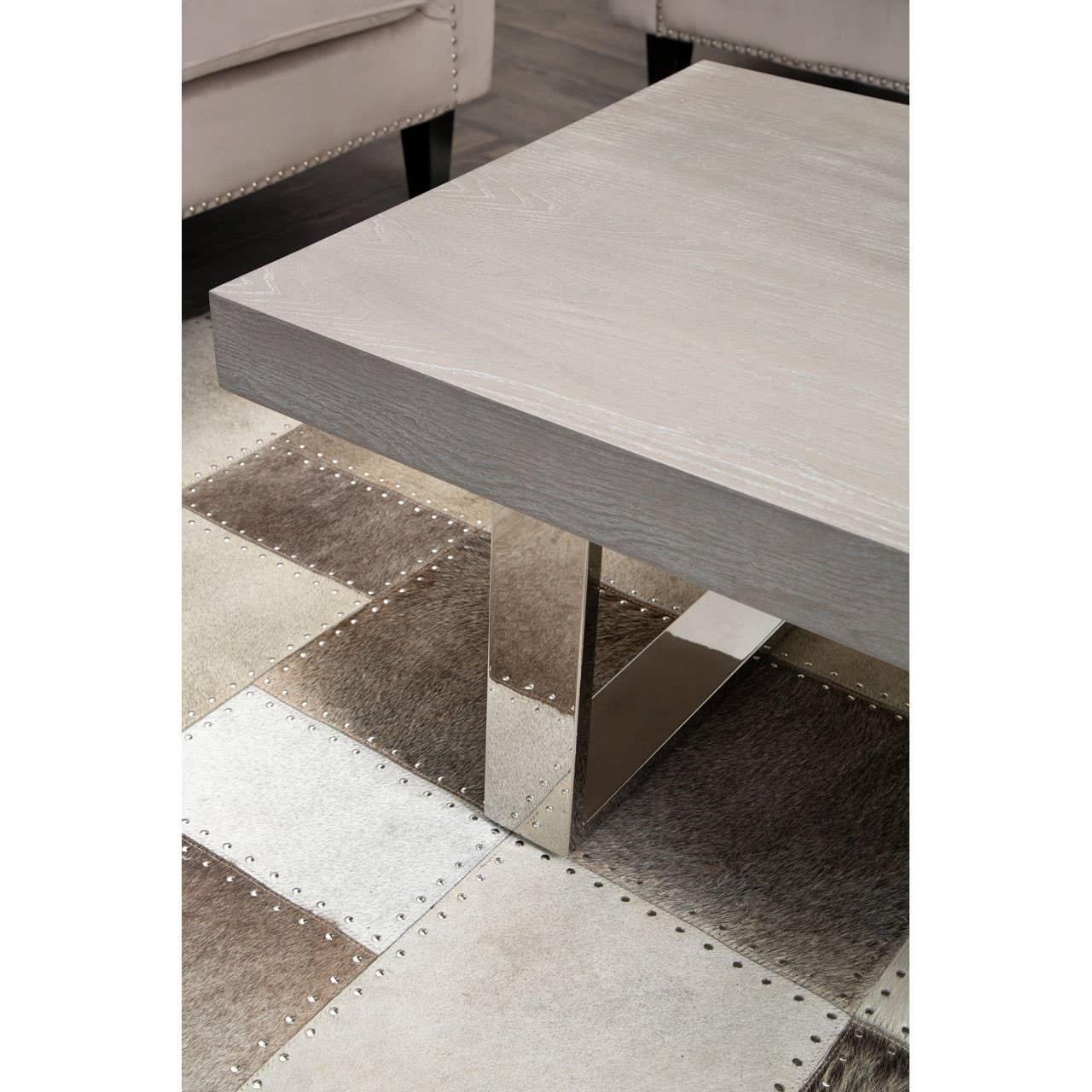 Modern square coffee table with light wood top and chrome legs on patchwork rug