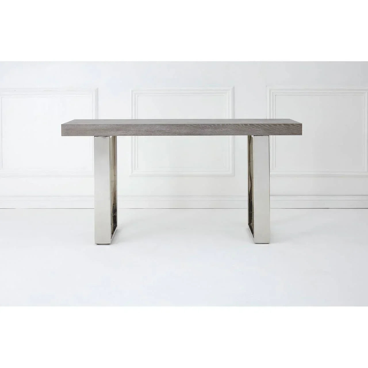 Modern console table with grey wood top and stainless steel legs against white wall
