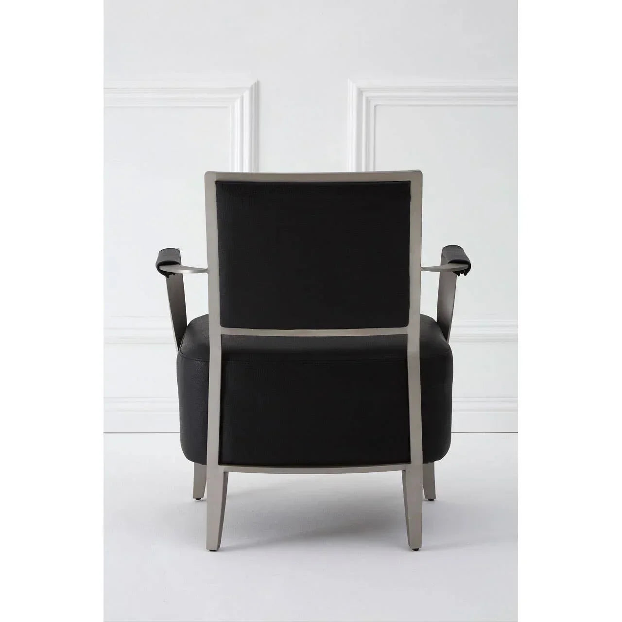 Back view of black armchair with metal frame against white wall