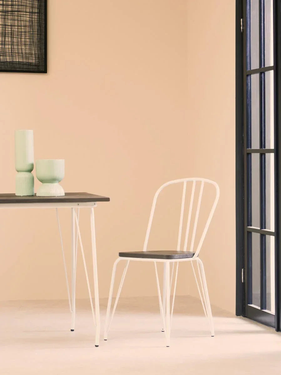 Modern dining chair with white metal frame and black seat next to minimalist table