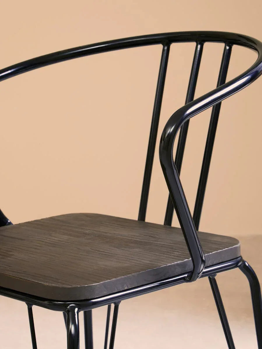 black metal dining chair with curved backrest and dark wood seat close-up