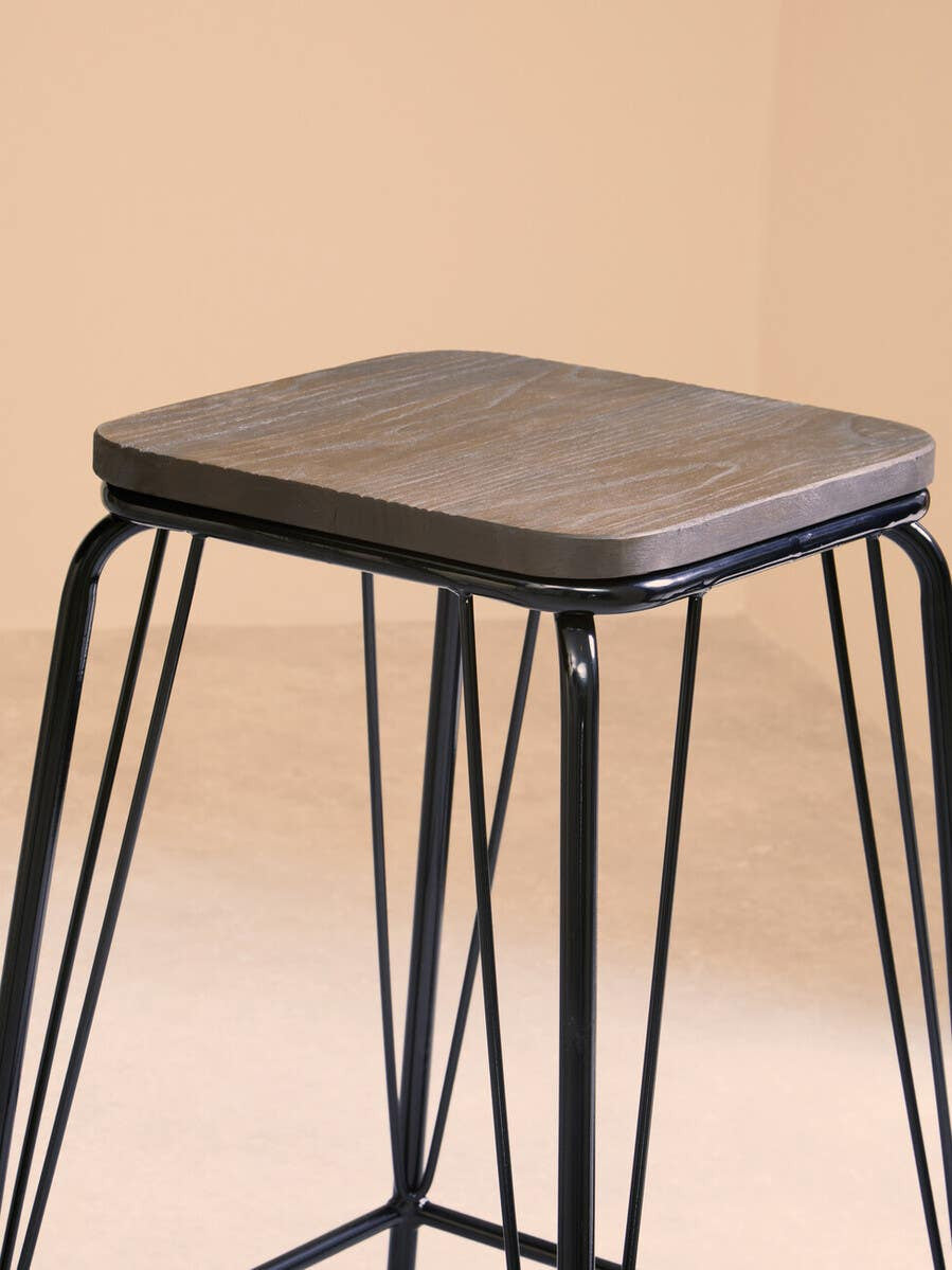 A black metal stool featuring a square elm wood seat, supported by slender, intersecting metal legs, set against a soft, neutral background