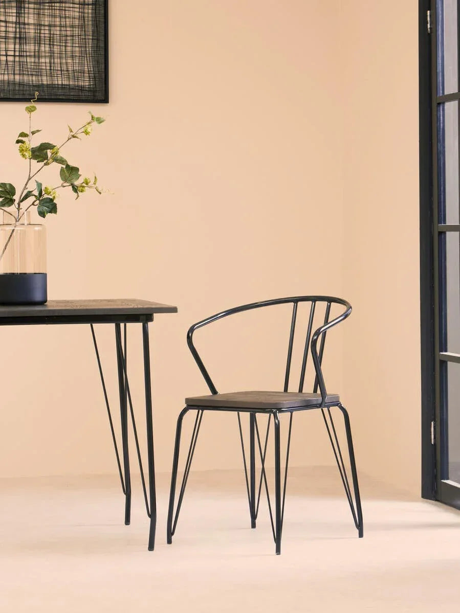 Black metal dining chair with curved backrest beside matching table in modern room