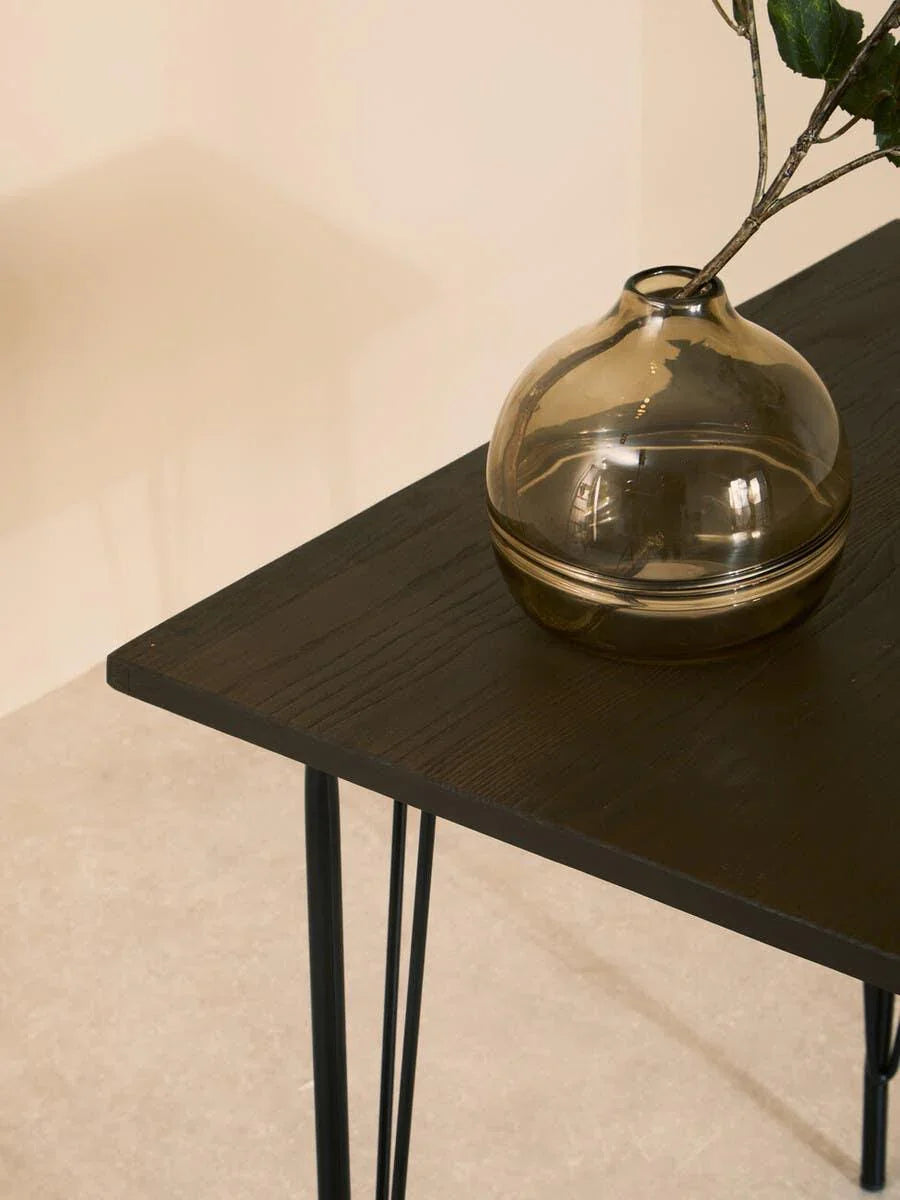 Black wood side table with metal hairpin legs and glass vase decor