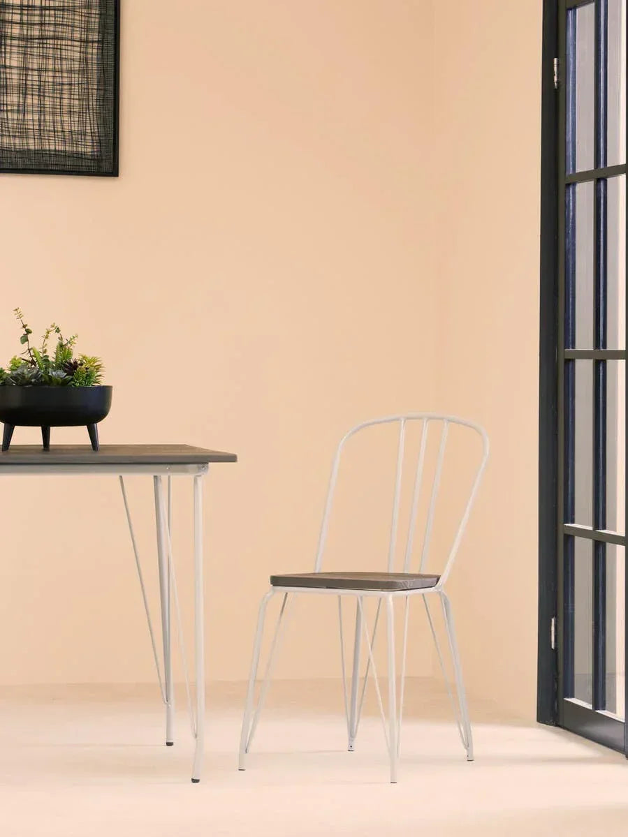 Grey metal dining chair with slim backrest next to matching dining table in bright room