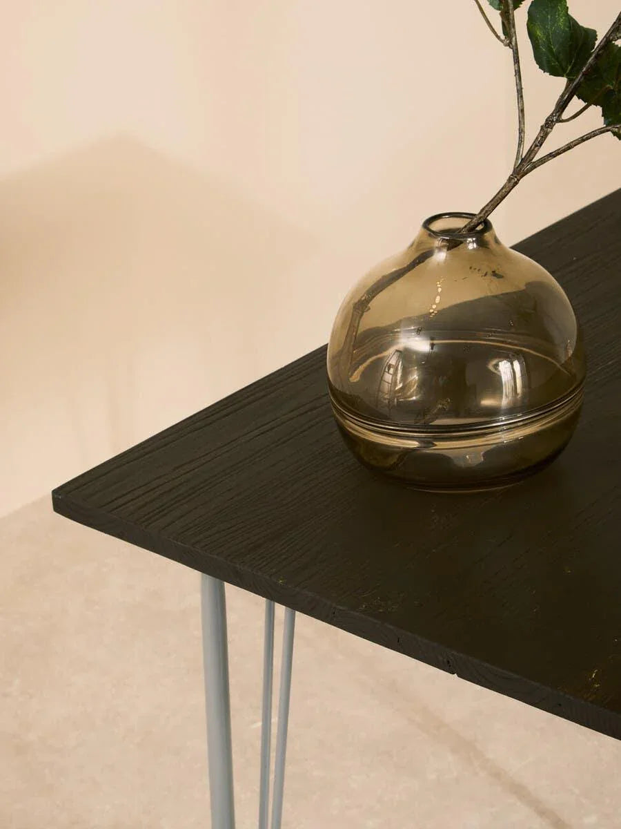 Black wood side table with metal legs and glass vase holding branches