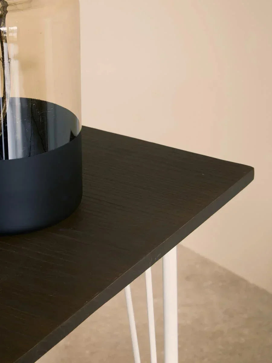 Dark wood side table with white metal legs and glass vase on tabletop