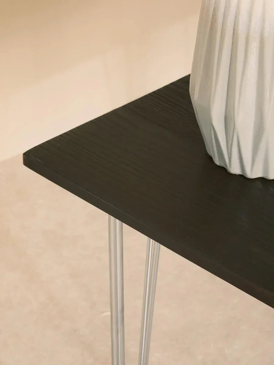 Black wood side table with slim metal legs and decorative ceramic vase corner detail