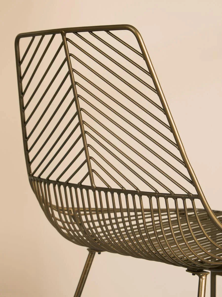 Metal dining chair with geometric wire backrest and seat, angled side view