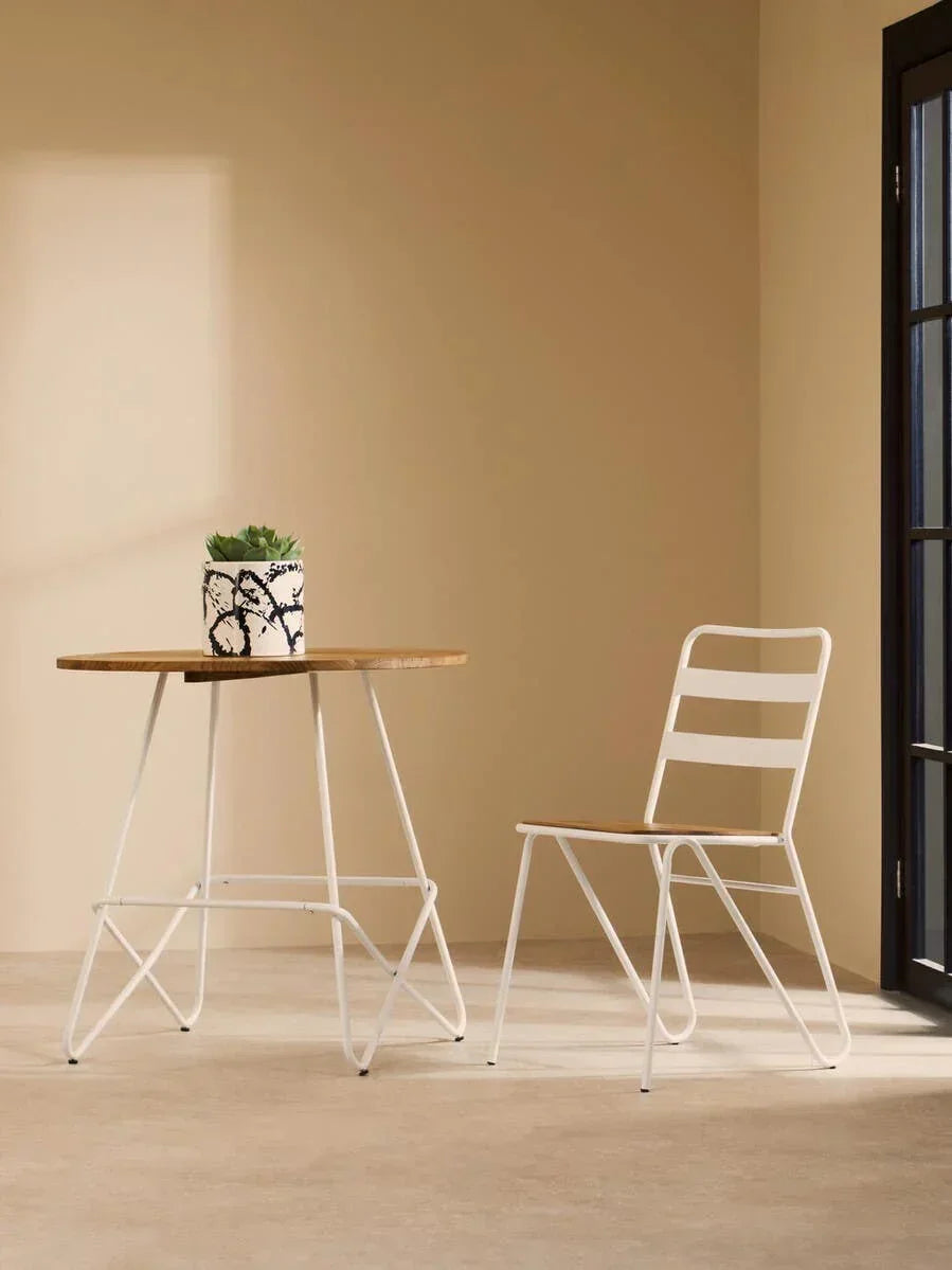 White metal and wood bistro table set with chair and plant in a modern indoor setting