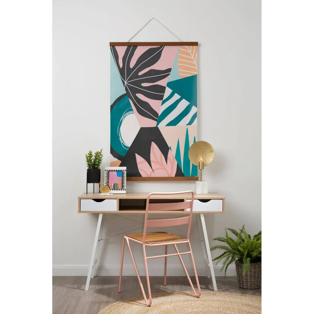 Modern writing desk with drawers, pink metal chair and abstract wall art in home office setup