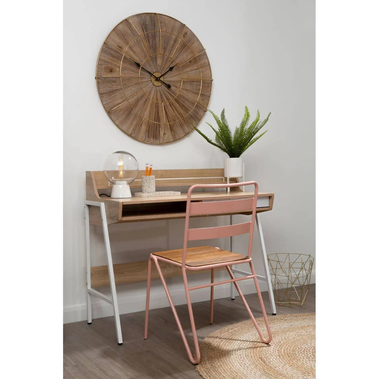 Wood desk and pink metal chair set with decor and large round wall clock