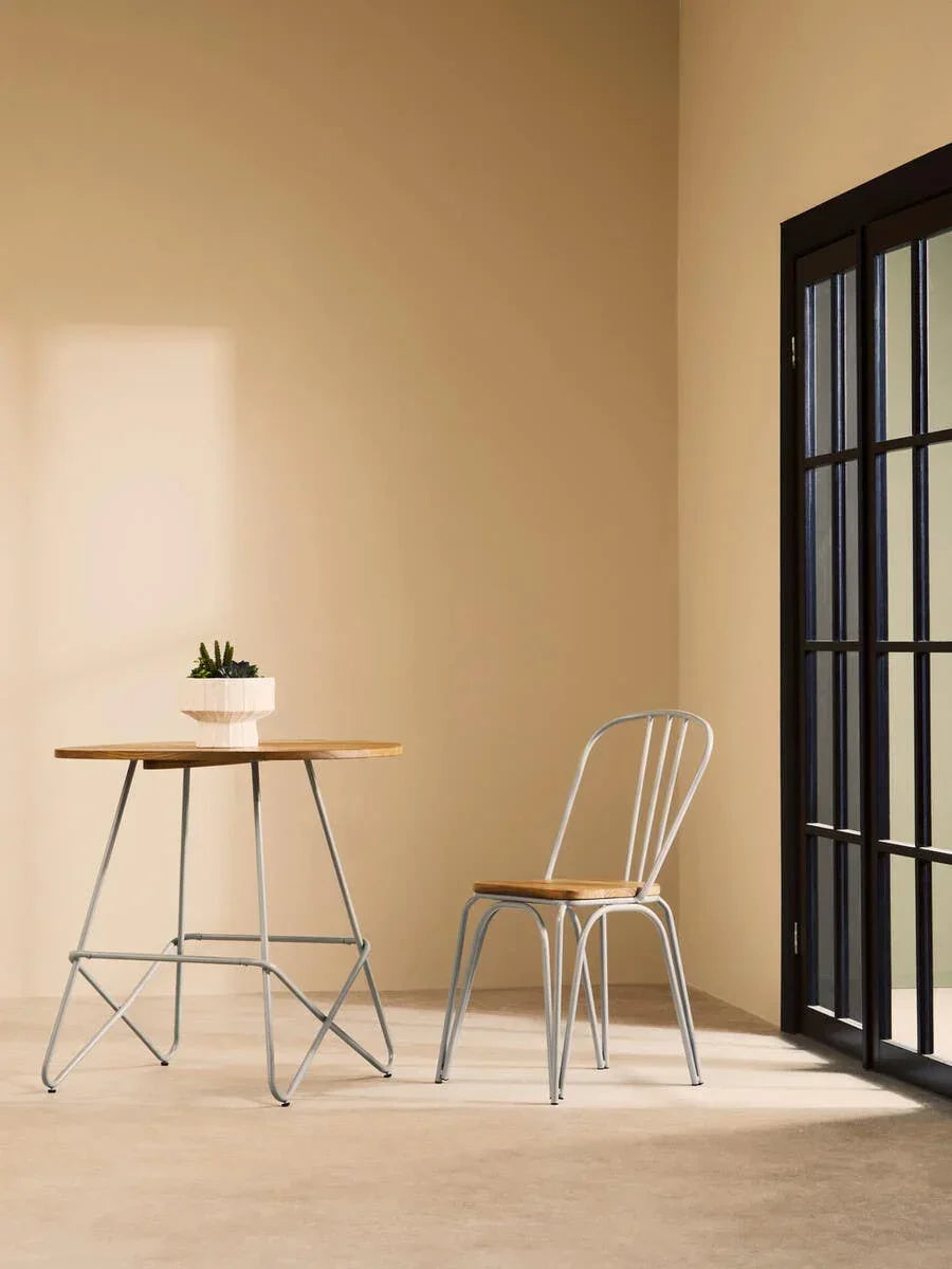 Modern dining table and chair set with light wood top and metal legs near window