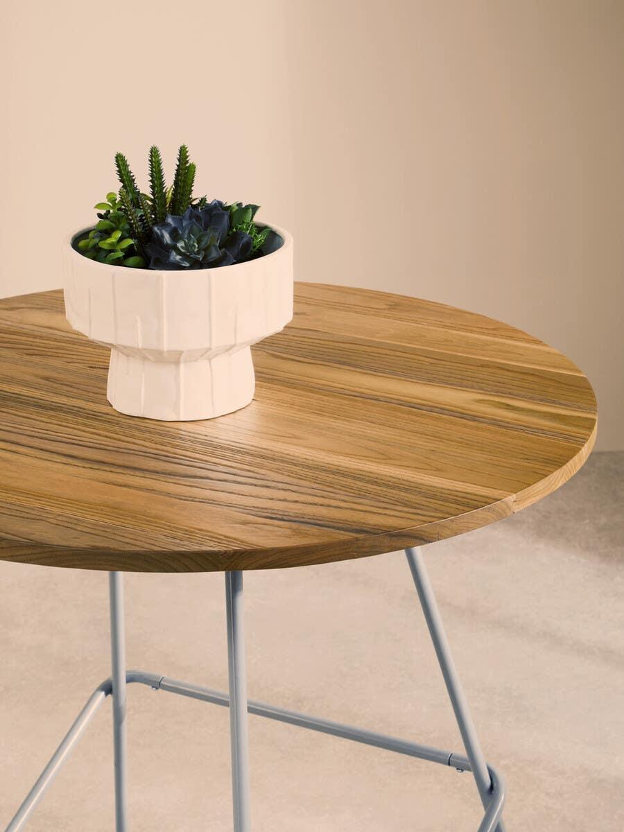Round wooden table with modern metal legs and ceramic planter with succulents