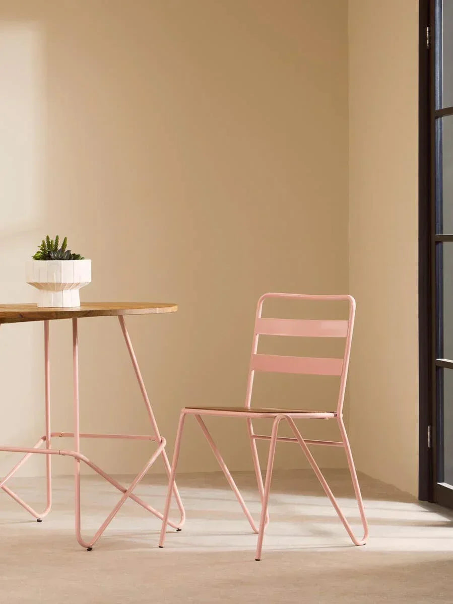 Pink metal dining chair and table set with wooden top in sunlit modern room