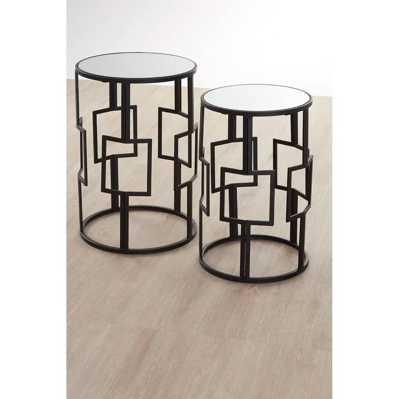 Modern black metal side tables with geometric design and round mirrored tops on wood floor