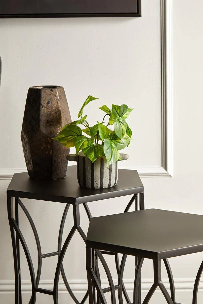 Black metal nesting tables with geometric legs, decorative vase and striped plant pot
