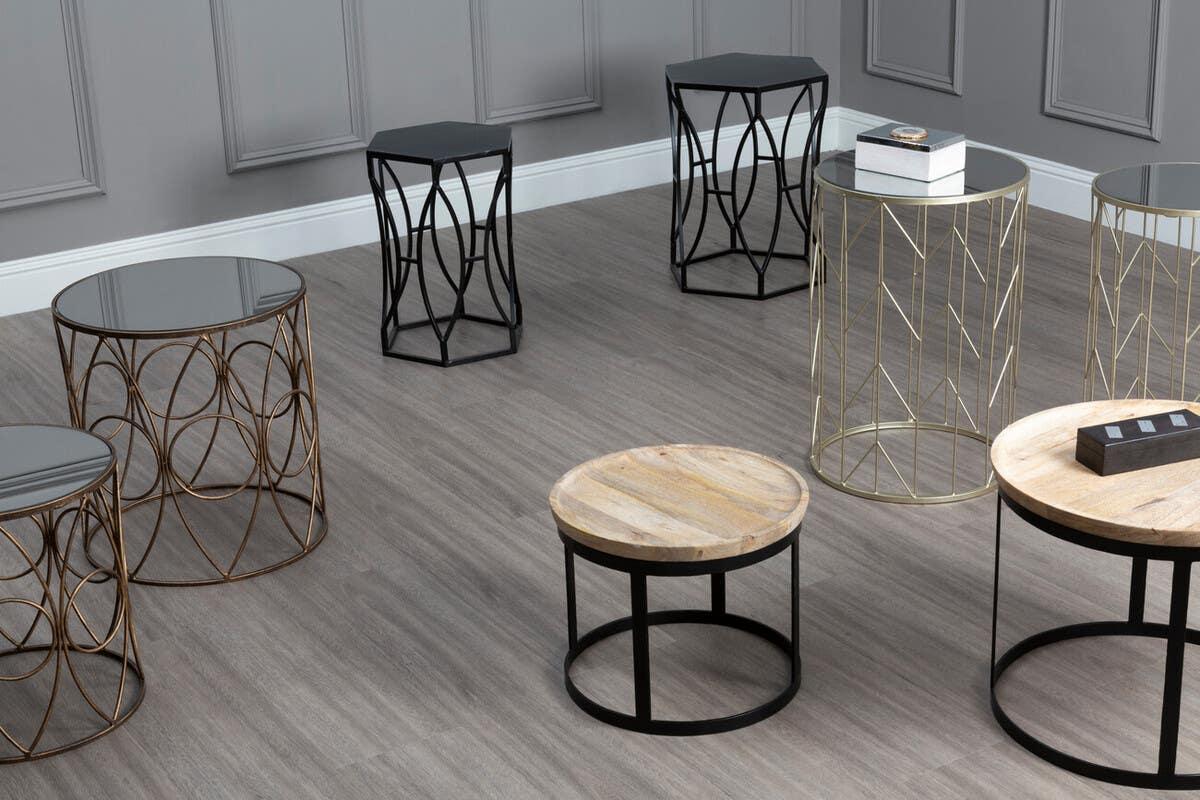 Assorted round metal and wood side tables on wood flooring in modern living room setting