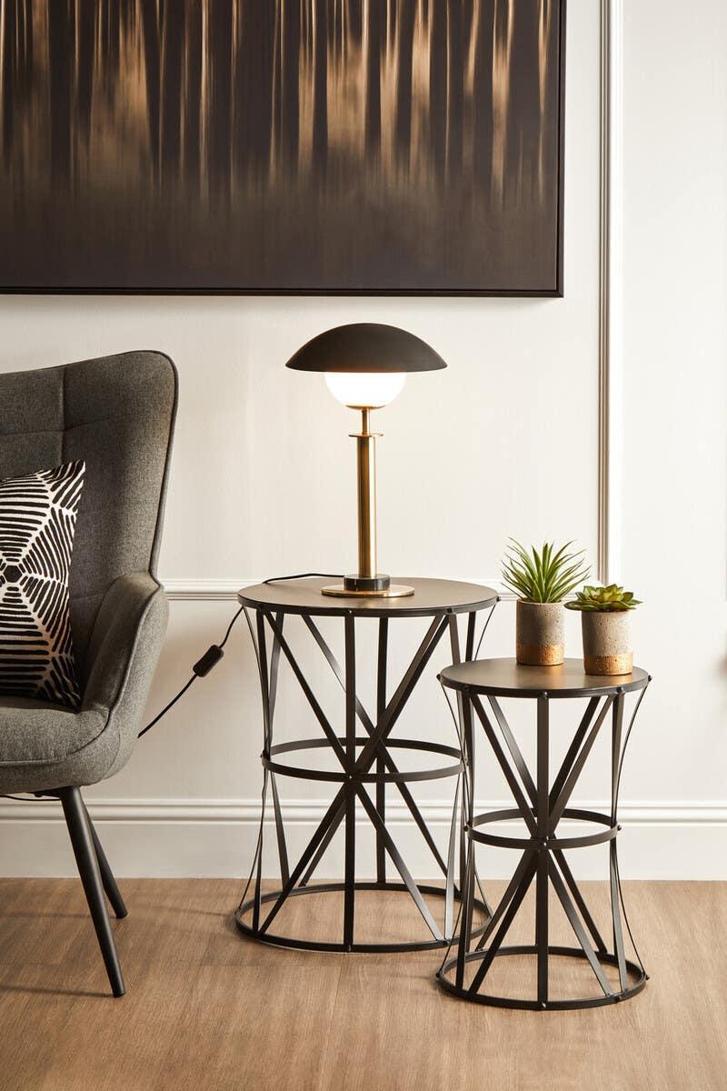 Modern black metal side tables with table lamp and potted plants in living room setting